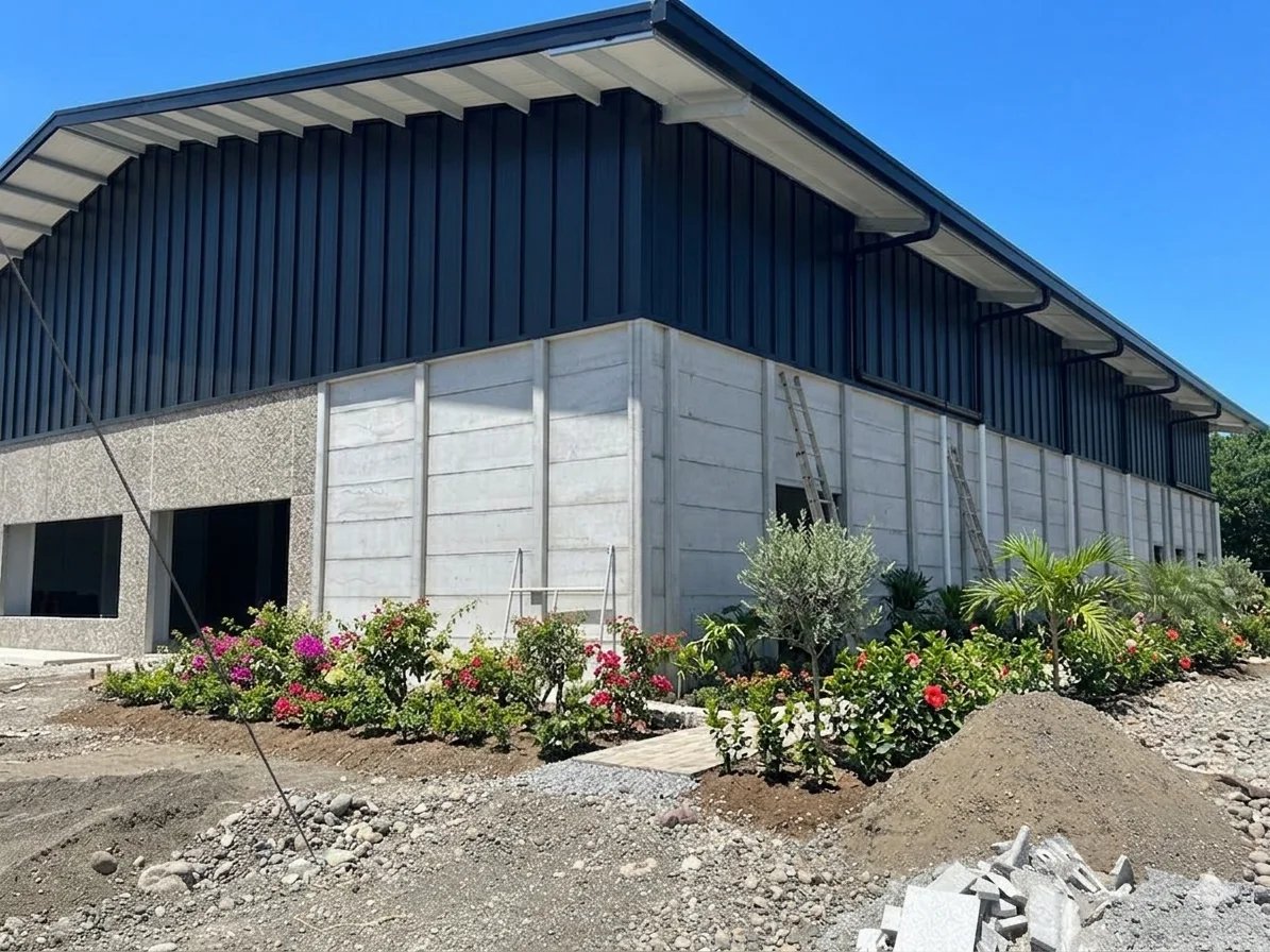 Bodega prefabricada con techo a dos aguas y muros de concreto en entorno con jardín exterior